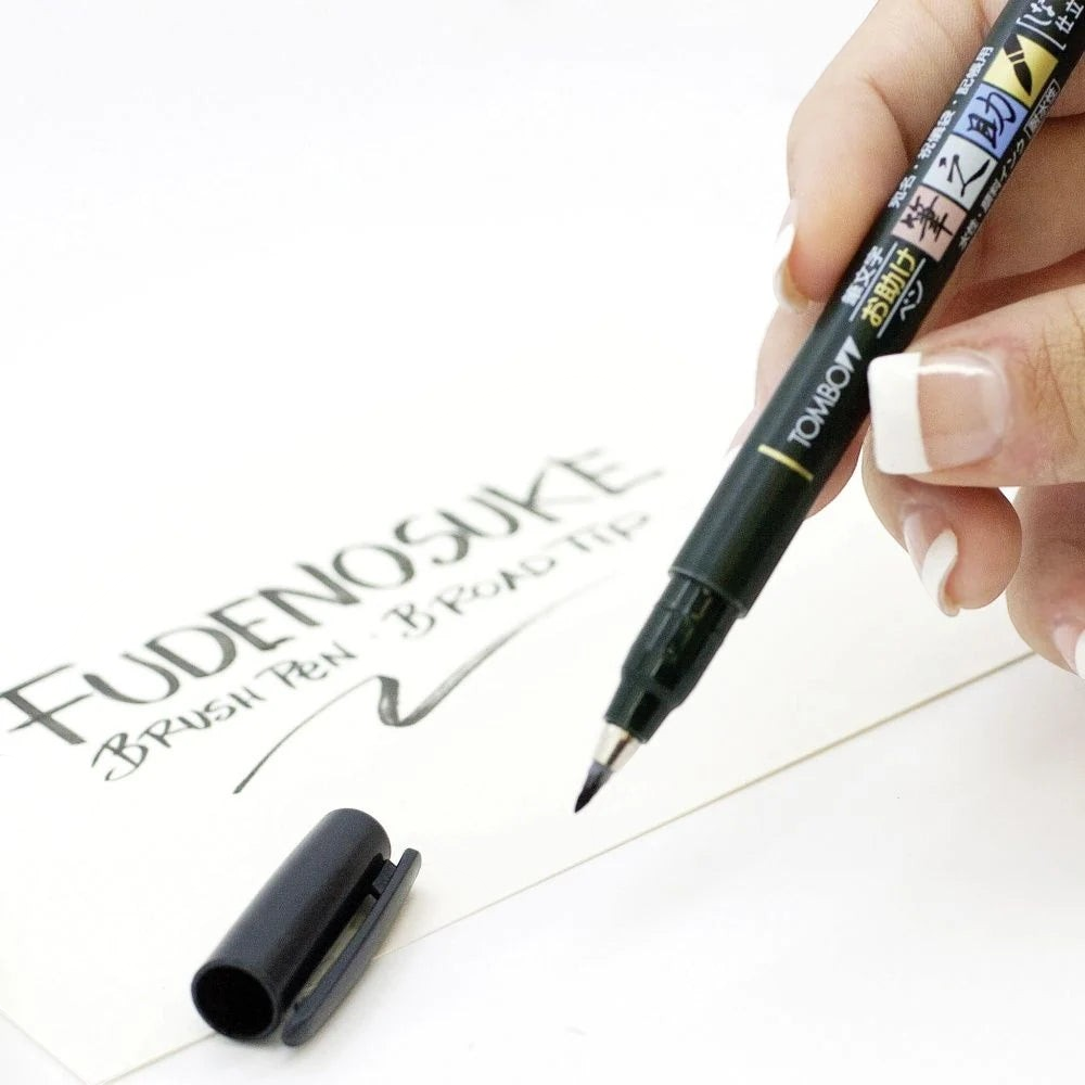 Eira Haul Tombow Fudenosuke soft tip black calligraphy brush pen held in hand writing on white paper