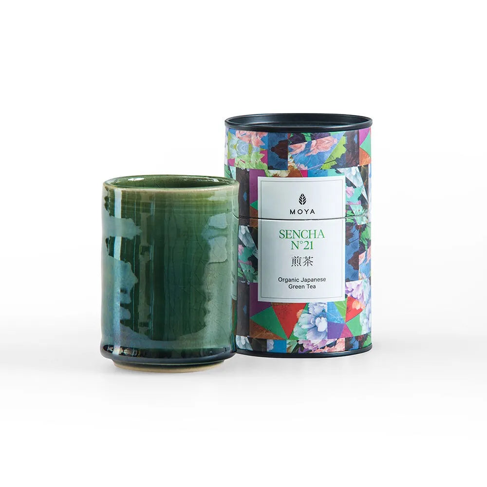 Eira Haul Moya Sencha No. 21 organic green tea tin and a handcrafted green stoneware Kasai mug on a white background.