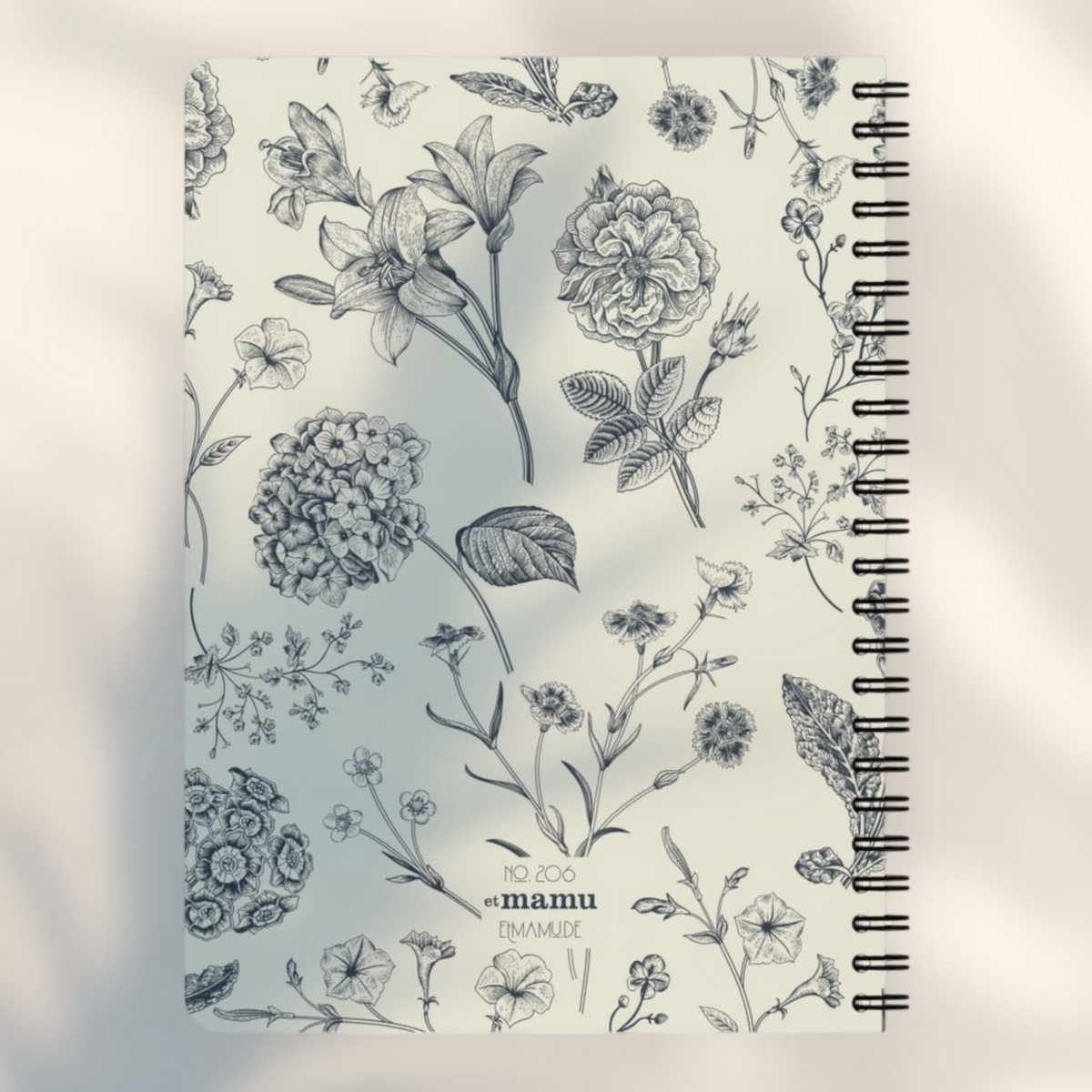 Eira Haul A5 spiral notepad with a cream cover featuring a detailed black botanical floral illustration pattern.