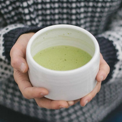 Eira Haul handmade ceramic matchawan bowl filled with frothy green matcha tea held in hands