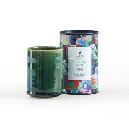 Eira Haul Moya Sencha No. 21 organic green tea tin and a handcrafted green stoneware Kasai mug on a white background.